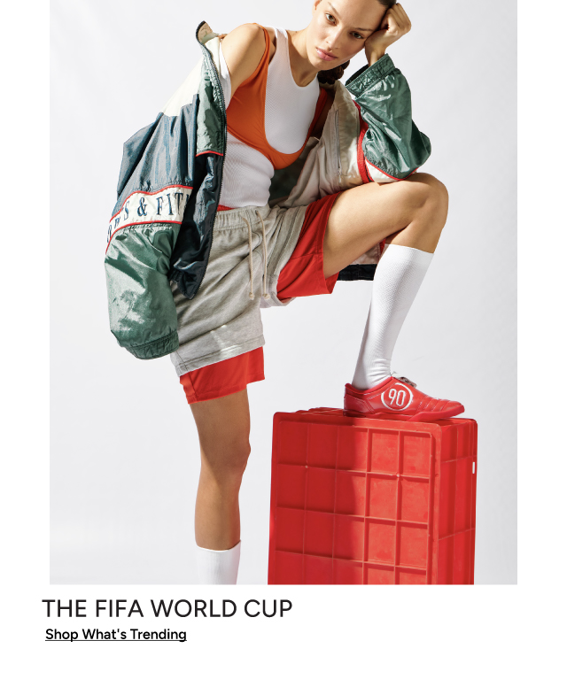 The FIFA World Cup — Shop What's Trending: woman posing in Nike sportswear, red shorts, and Nike 90 cleats on a red crate.