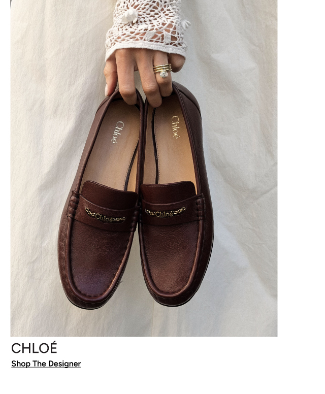 Chloé brown leather loafers with gold logo detail, held by a hand — Shop The Designer
